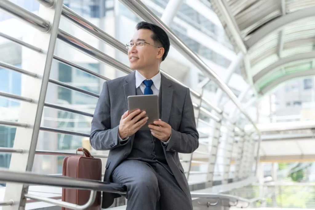 Asian man in an airport holding a tablet