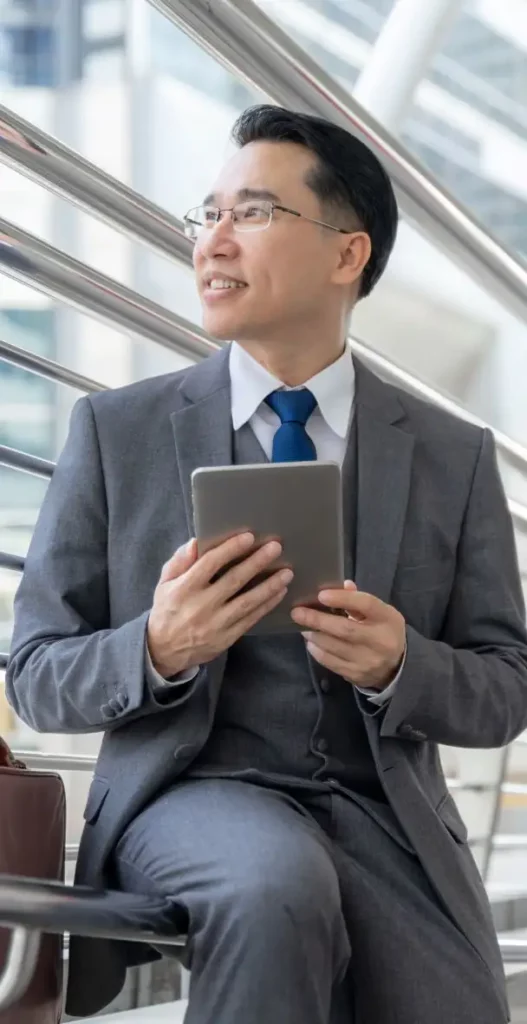 IE Business School Asian man in an airport holding a tablet